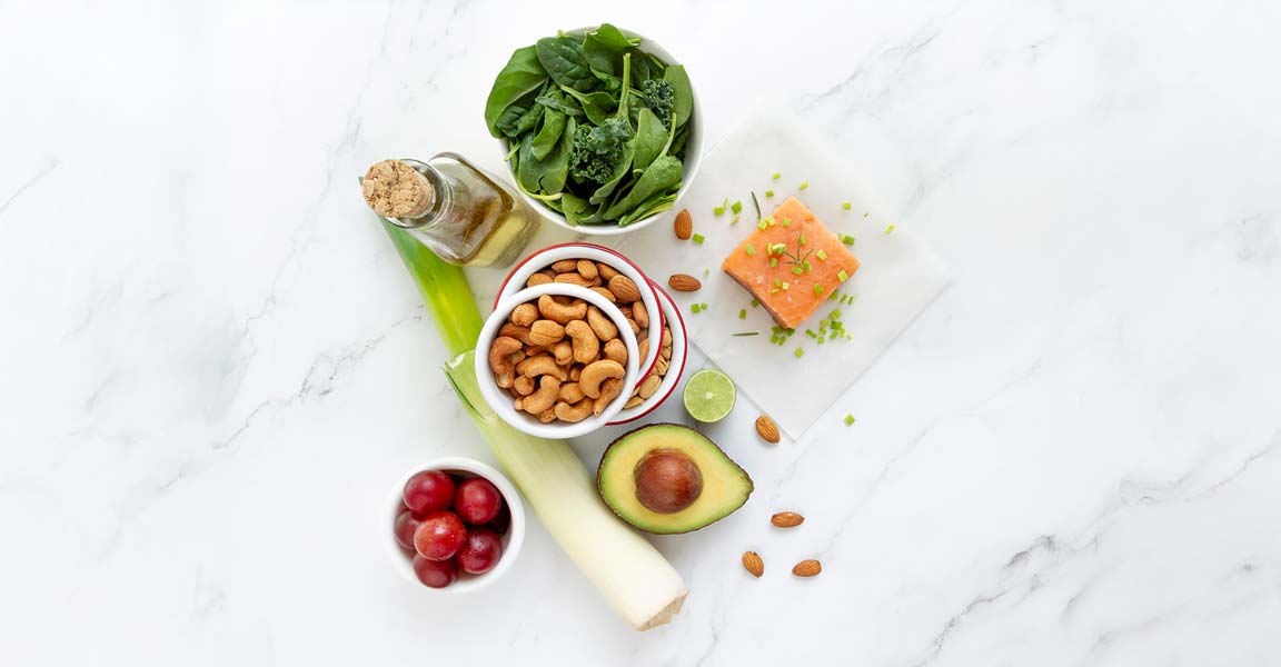 Fotografía de alimentos naturales y saludables: puerros, espinacas, salmón, anacardos, uvas, aguacate...